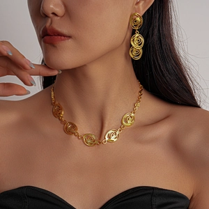 Détail du parure collier et boucles d'oreilles fleurs ajourées dorées sur mannequin