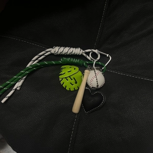 Detailed view of mini baseball keychain with green leather glove and wooden bat charms