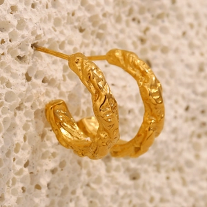 Dettaglio macro di orecchini in acciaio inossidabile placcato oro 18K con trama martellata