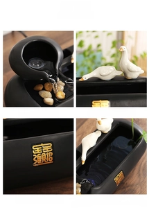 Detail view of ceramic water fountain with gold calligraphy and lucky duck ornament