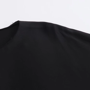 Détails du t-shirt noir asymétrique montrant la manche en dentelle et les coutures