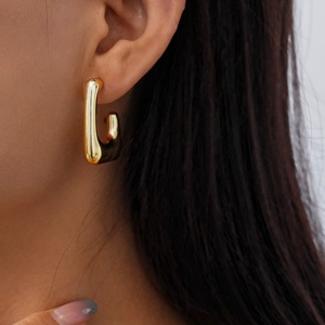 Close-up of a polished gold J-shaped earring worn by a model for a stylish look