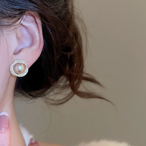 Close-up of gold pearl tassel earrings with diamonds worn on ear for elegant style