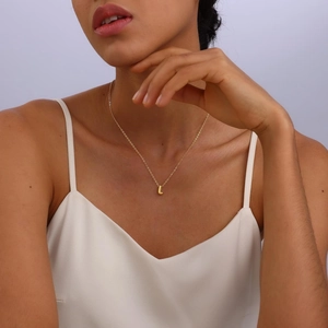 Close-up of a gold bubble letter L pendant necklace on model's neck for a trendy look