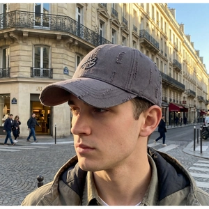 Close-up of distressed grey baseball cap with 3D letter embroidery in a street setting