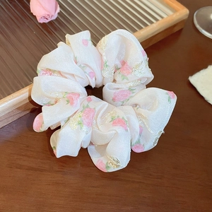 Détail du chouchou en dentelle à fleurs roses avec broderie fine sur tissu en mousseline