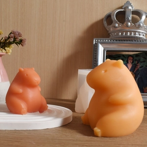DIY silicone mold and finished capybara scented candles on a warm wooden background