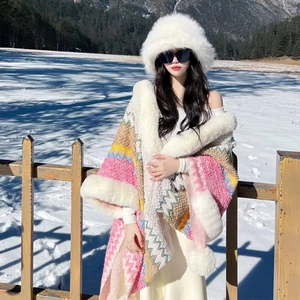 Detail of colorful zigzag knit shawl with white faux fur trim on snowy outdoor background
