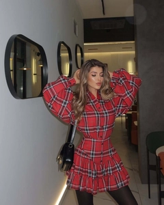 Detailed close-up of red plaid dress with ruffled hem and elegant textured check pattern