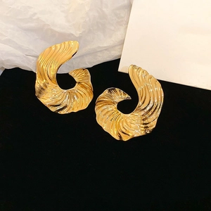 Detail view of irregular textured golden shell-shaped earrings on elegant black velvet