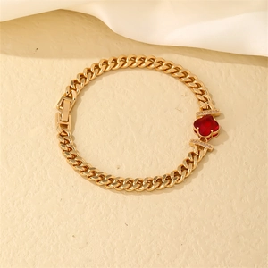 Detailed macro of gold Cuban link bracelet with red clover pendant and zircon inlay