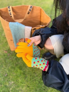 Outdoor shot of bright yellow knitted winter gloves with blue polka dot wrist cuffs