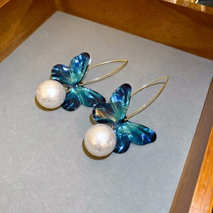 Detail of blue marble butterfly wings and large white pearl drops on gold ear hooks