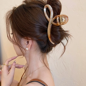 Close-up of a large amber tortoiseshell hair claw clip securing a woman's hair bun