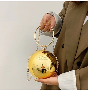 Dettaglio borsa da sera sferica dorata con manico metallico e finitura a specchio
