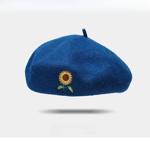 Close-up of wool beret featuring detailed sunflower embroidery on navy blue fabric