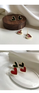 Macro detail of heart-shaped enamel earrings in dark green and red on silk fabric