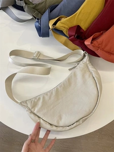 Flat lay of minimalist nylon crescent bags in various colors with adjustable straps