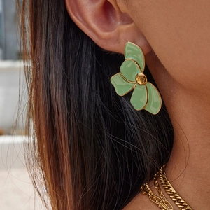Close-up of a model wearing a light green enamel flower earring with 18K gold edges
