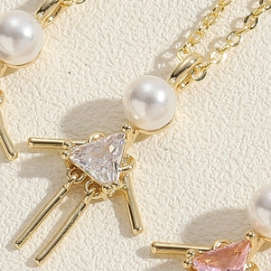 Detailed close-up of cute cartoon girl pendants with pearls and zircon on gold chains