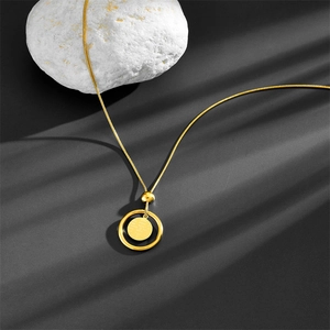 Détail du pendentif double anneau doré avec gravure d'écriture sur chaîne serpent fine