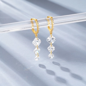 Detail of gold-plated silver earrings featuring three square-cut sparkling zircons