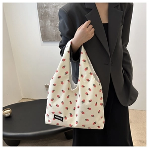 Detail view of corduroy tote bag with strawberry prints and a black fashion woven label