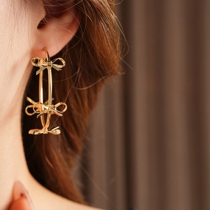 Close-up of elegant gold hoop earrings with small bows worn by a female model