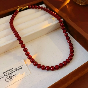 Detail of red bead necklace with gold clasp on premium velvet jewelry display tray