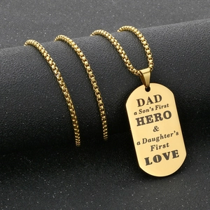 Polished gold dog tag necklace with Dad Hero engraving on a textured black surface