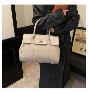 Close-up of cream beige leather tote bag with gold twist lock on a wool coat