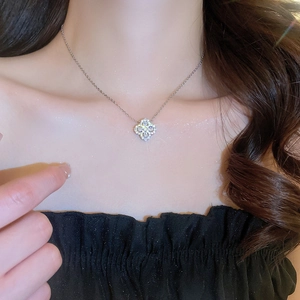 Close-up of sparkling silver four-leaf clover pendant necklace worn by a model