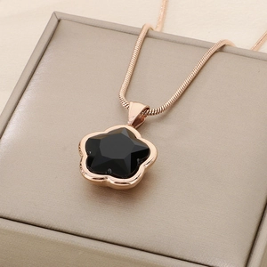 Macro shot of rose gold flower pendant with black faceted stone on a snake chain