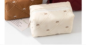 Close-up of quilted makeup bags with ribbon embroidery in cream, brown, and red colors