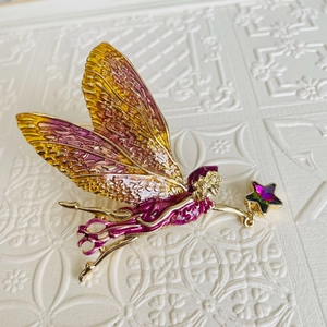 Macro shot of colorful enamel fairy brooch with gradient wings and a purple star