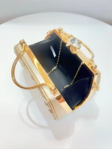 Close-up of golden evening clutch with pearls, rhinestones, and chain strap inside