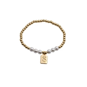 Detail of beaded bracelet with gold beads, white pearls, and gold square S letter charm