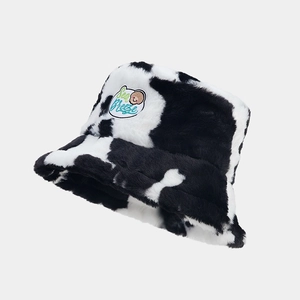 Close-up of cow print plush bucket hat featuring sea breeze embroidered patch detail