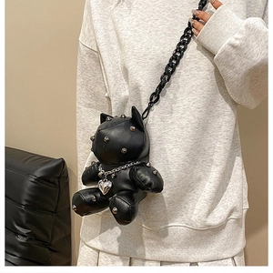 Detail of black leather bear crossbody bag with metal rivets and chunky chain strap