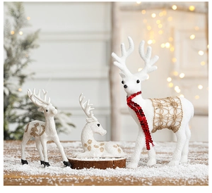 Detailed view of three white reindeer figurines with red and gold accents on snow