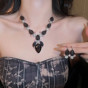 Close-up of black teardrop gemstone necklace and earrings set with pink and white diamonds