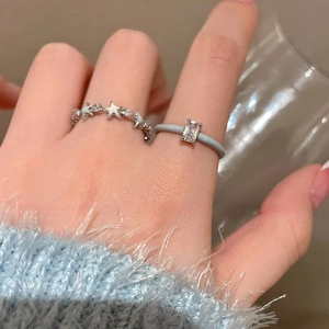 Macro detail of silver star rings and blue zircon ring on a model hand with blue sweater