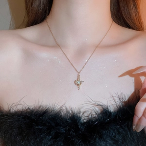 Dettaglio di una collana con ciondolo a croce dorata con zirconi sul collo