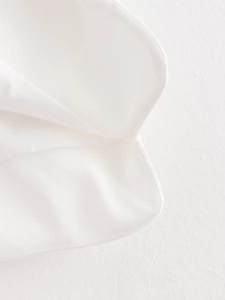 Macro detail of the white fabric's twill texture and precision stitched edge finish