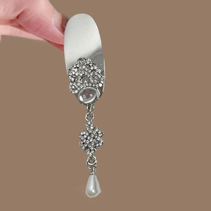 Macro view of silver nail armor ring featuring sparkling rhinestones and pearl tassels