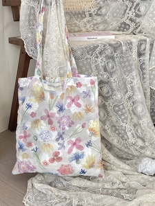 Floral mesh tote bag with colorful embroidery and long handles in a lifestyle setting