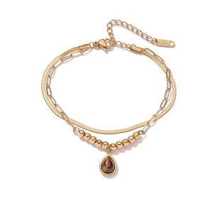 Detail of gold double-layered bracelet with snake chain and brown gemstone pendant