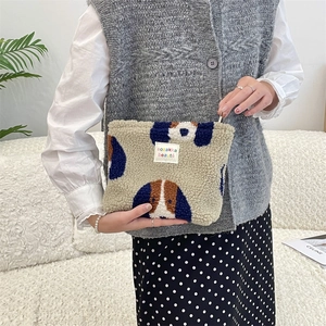 Close-up of plush fleece makeup bag with dog pattern and branded fabric label