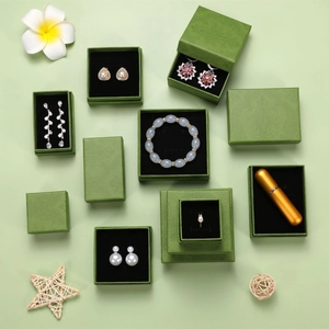 Flat lay of green enamel jewelry boxes showing pearls and gemstones in macro detail