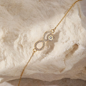 Macro shot of gold infinity necklace with shimmering cubic zirconia on stone background